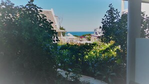A view from a balcony overlooking a garden with a pool and a building in the background. - Misty Waves Boutique Hotel (Hermanus)