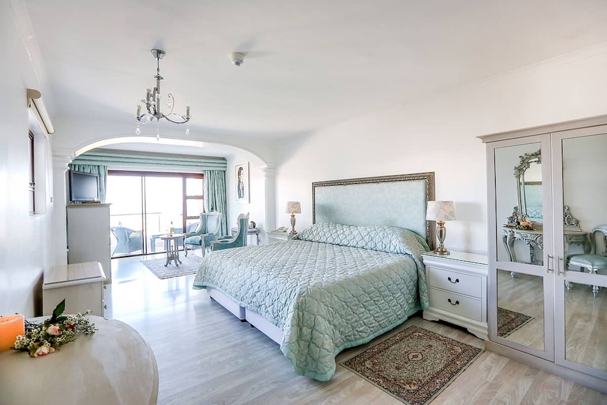 Une chambre spacieuse avec un grand lit, une armoire, un lustre et une vue sur l’extérieur.