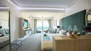 A modern hotel room with a bed, a desk, a bench, and a view of the ocean. - Misty Waves Boutique Hotel (Hermanus)