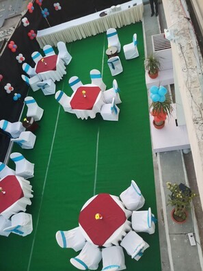 An outdoor seating area with round tables and white chairs, arranged on a green carpet. - The Wall Street Beacon, Jaipur (Jaipur)