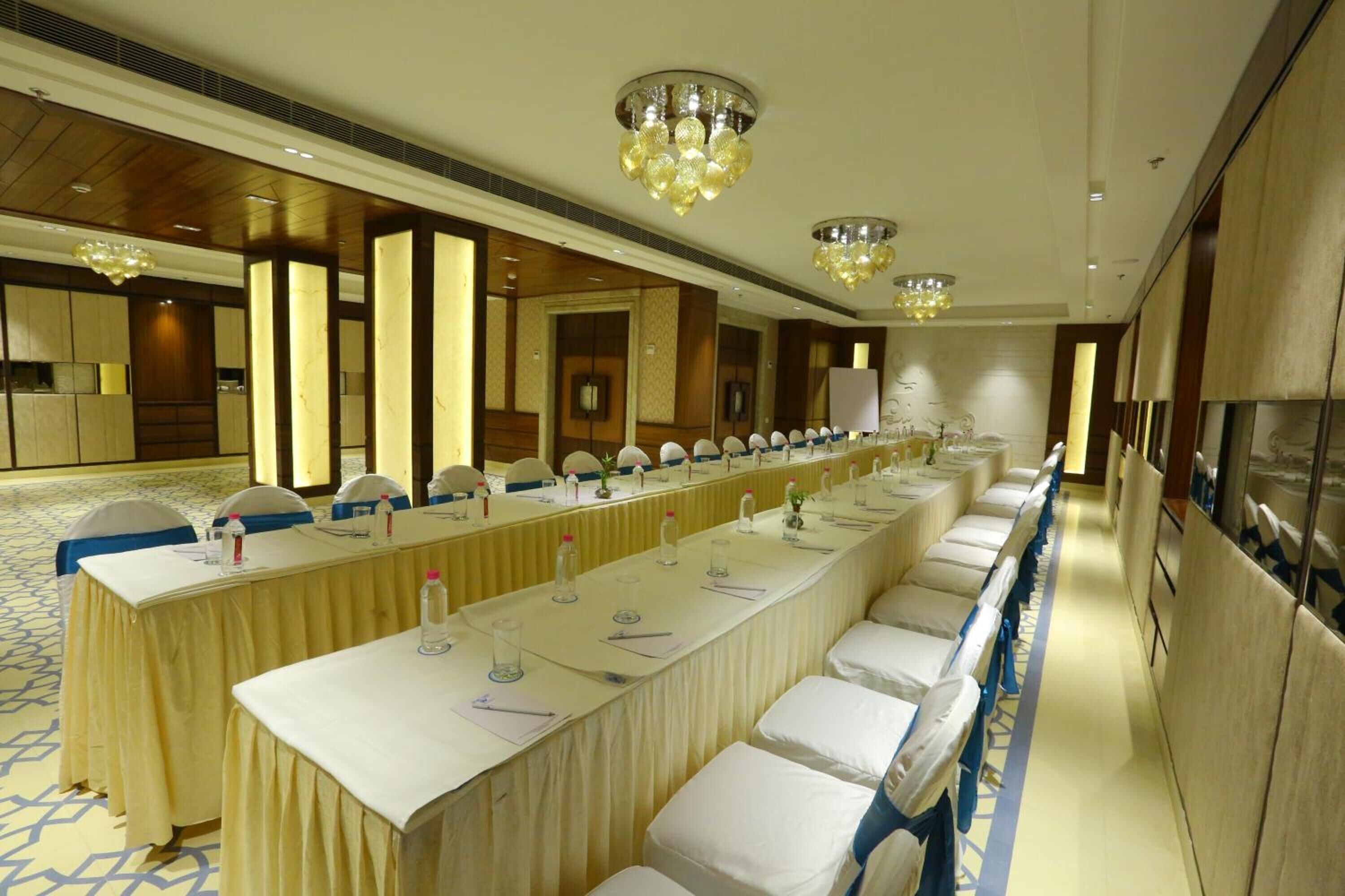 Uma longa mesa de banquete com cadeiras, um candelabro e um espelho.