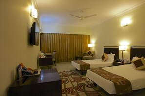 A hotel room with two beds, a desk, a chair, a TV, and a ceiling fan. - The Wall Street Beacon, Jaipur (Jaipur)