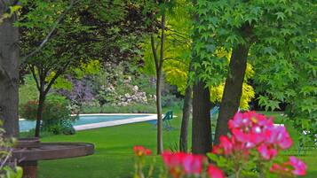 Escape to a serene garden oasis with a tranquil atmosphere, featuring a swimming pool and lush greenery.