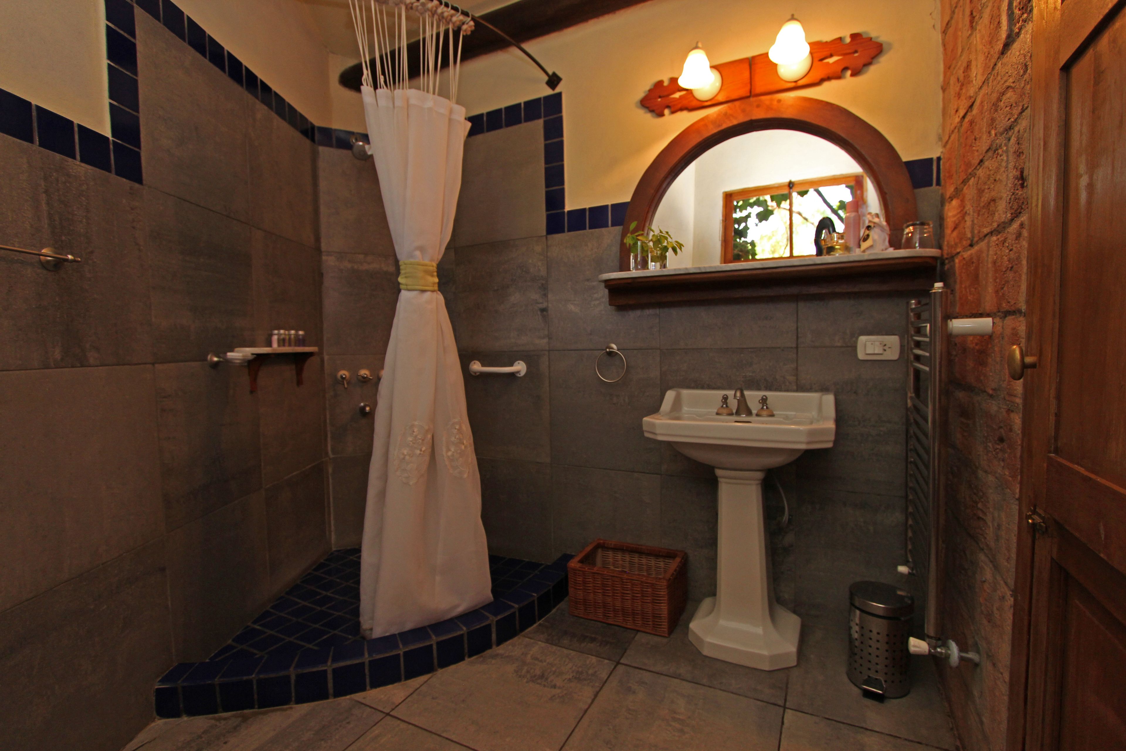 A bathroom with a shower, a sink, and a mirror.
