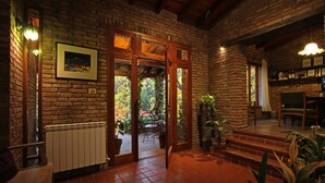 A brick-walled interior with a wooden door leading to a garden. - Casa Glebinias Hotel Jardin (Chacras de Coria)
