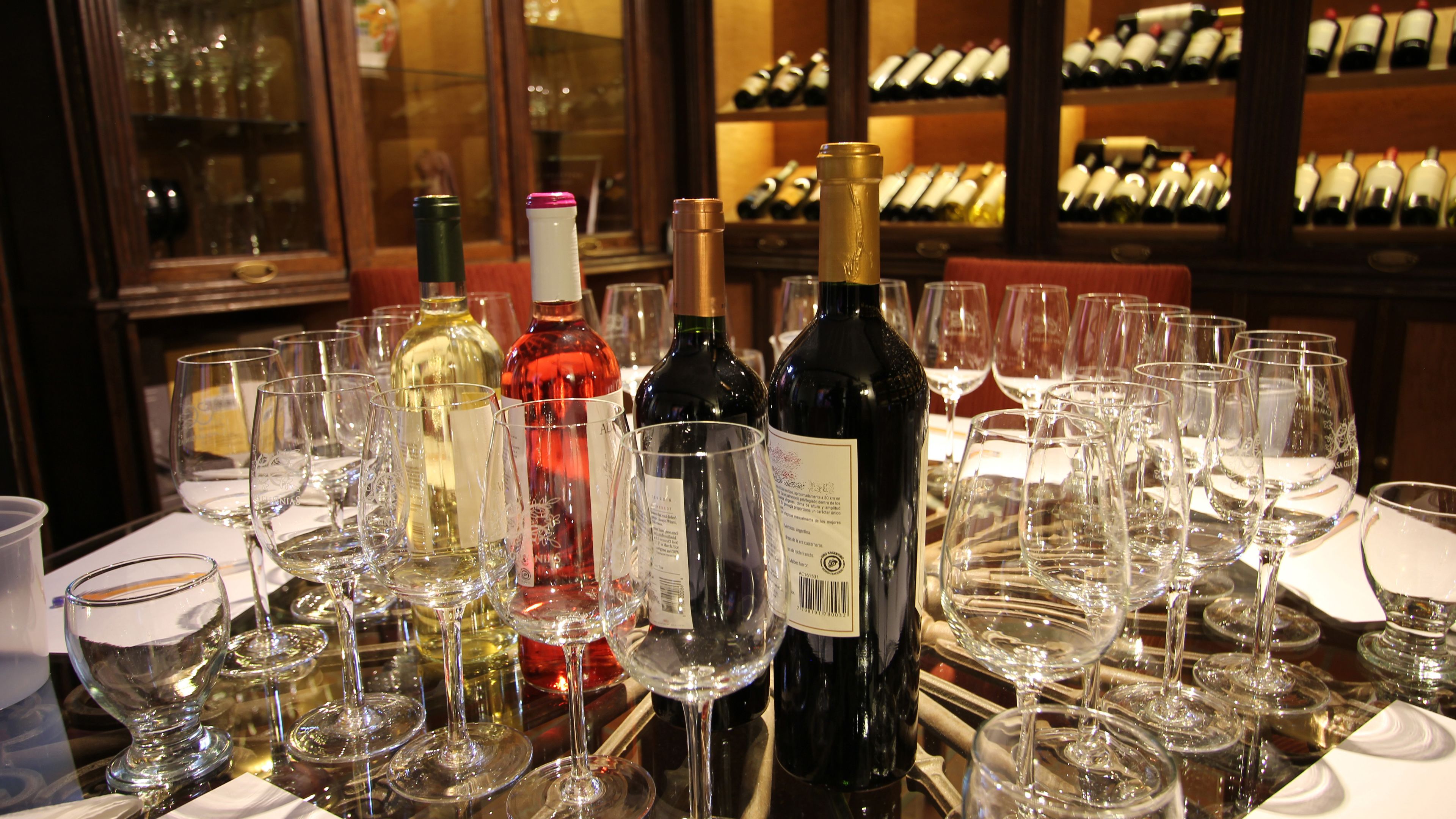 A table with multiple wine bottles and glasses, likely in a restaurant or bar setting.