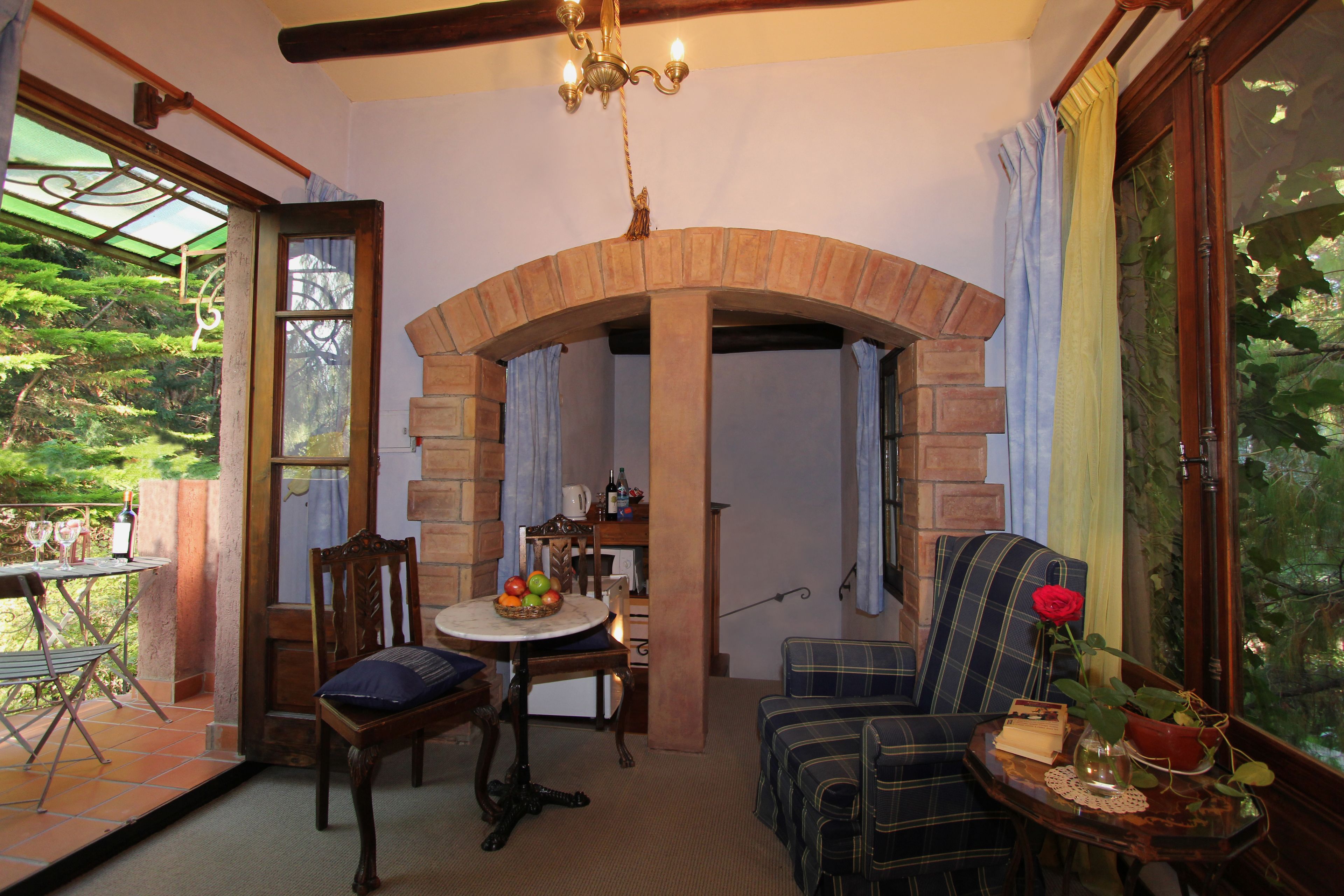 Una habitación acogedora con un arco de madera, una mesa de comedor con fruta, un sofá y vistas a la vegetación.