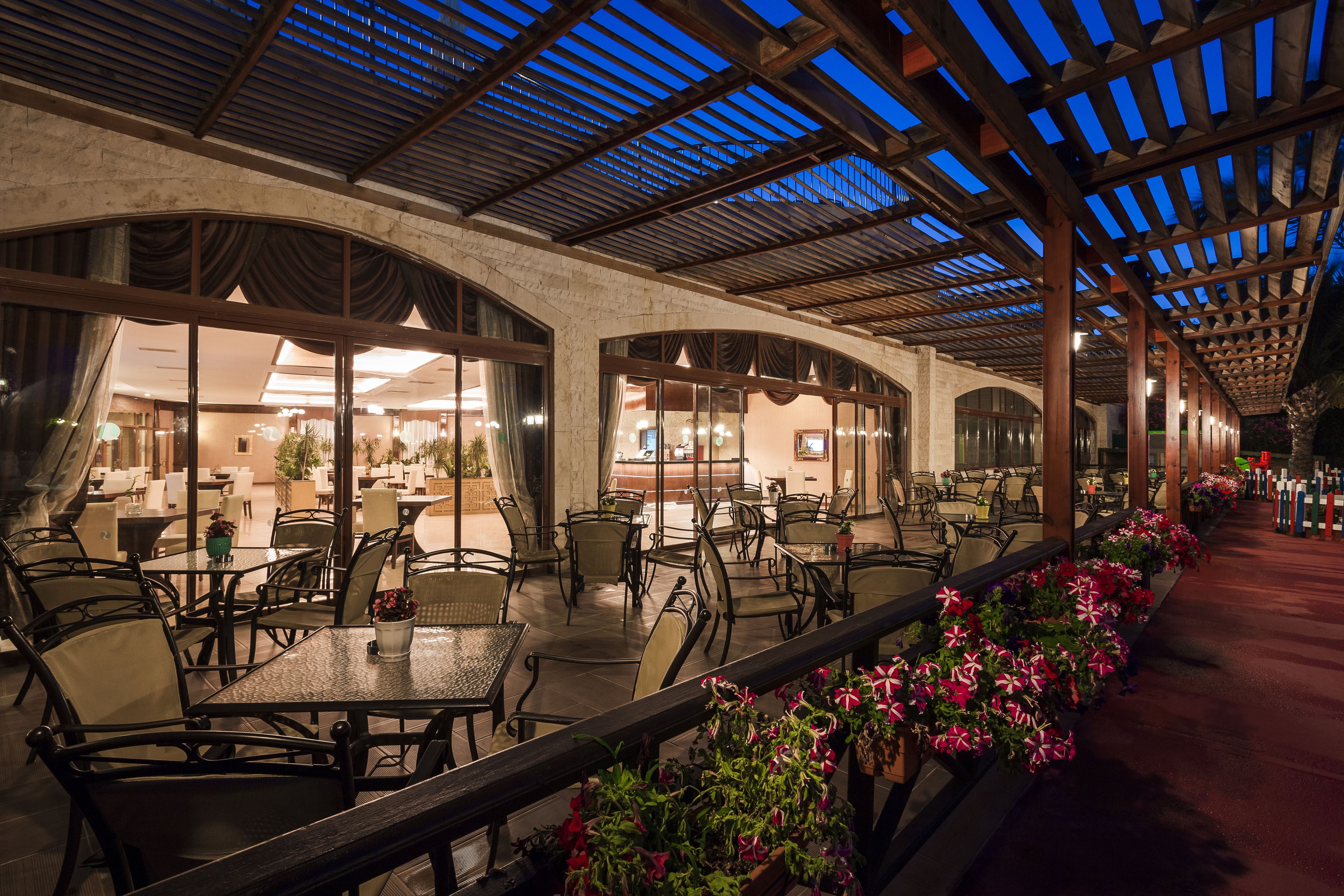 An indoor patio area with tables and chairs, a covered walkway, and potted plants along the path.