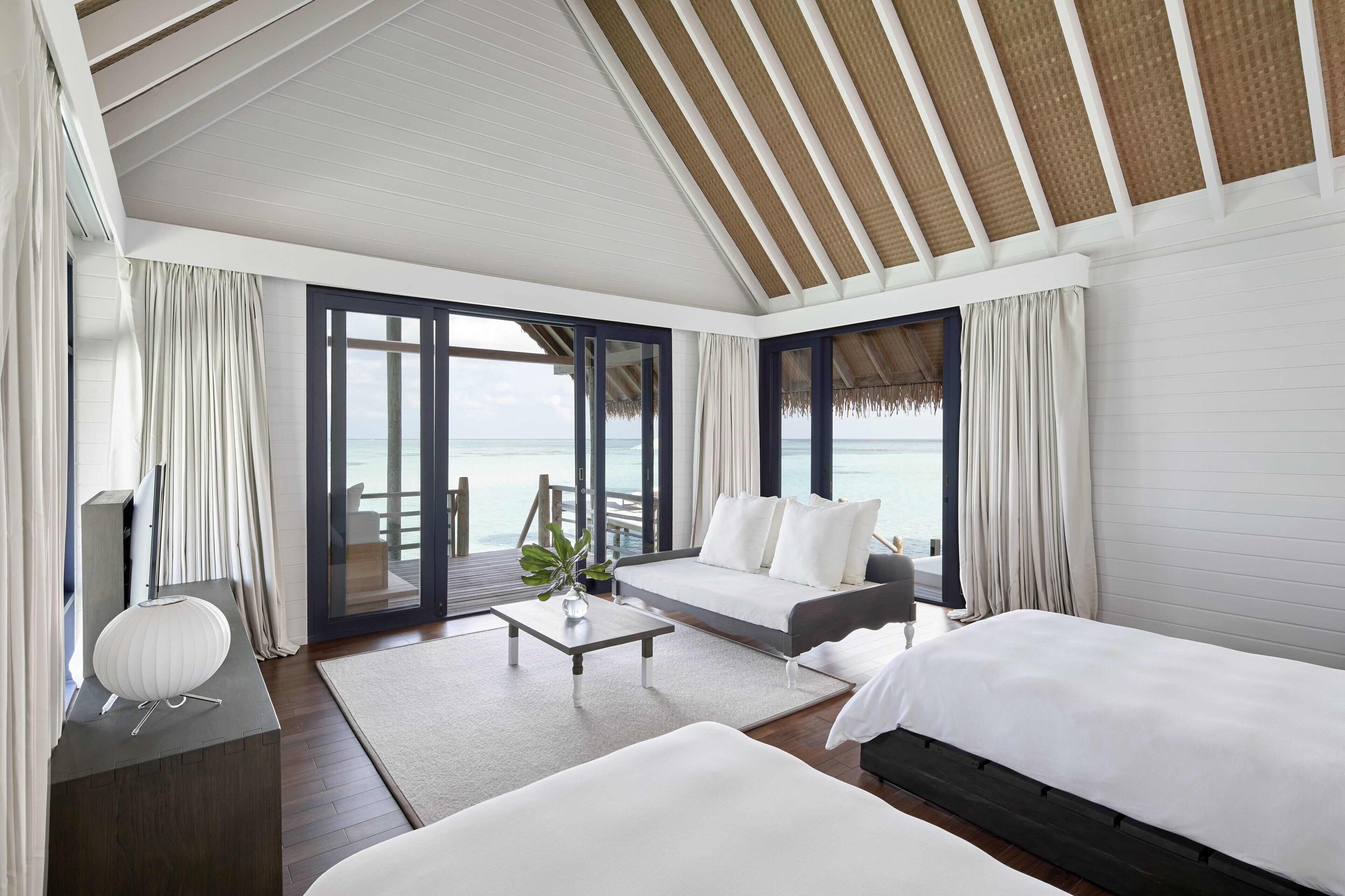 Una habitación de hotel moderna con balcón, un sofá, una cama y un escritorio.