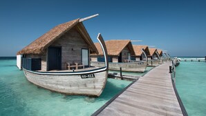 Cabañas sobre el agua con techos de paja, pasarelas de madera y agua turquesa cristalina.