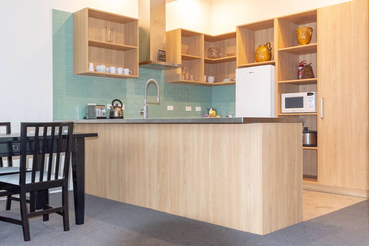 Eine moderne Küche mit Holzausstattung, einer zentralen Kochinsel, einem Spülbecken und einer Mikrowelle.