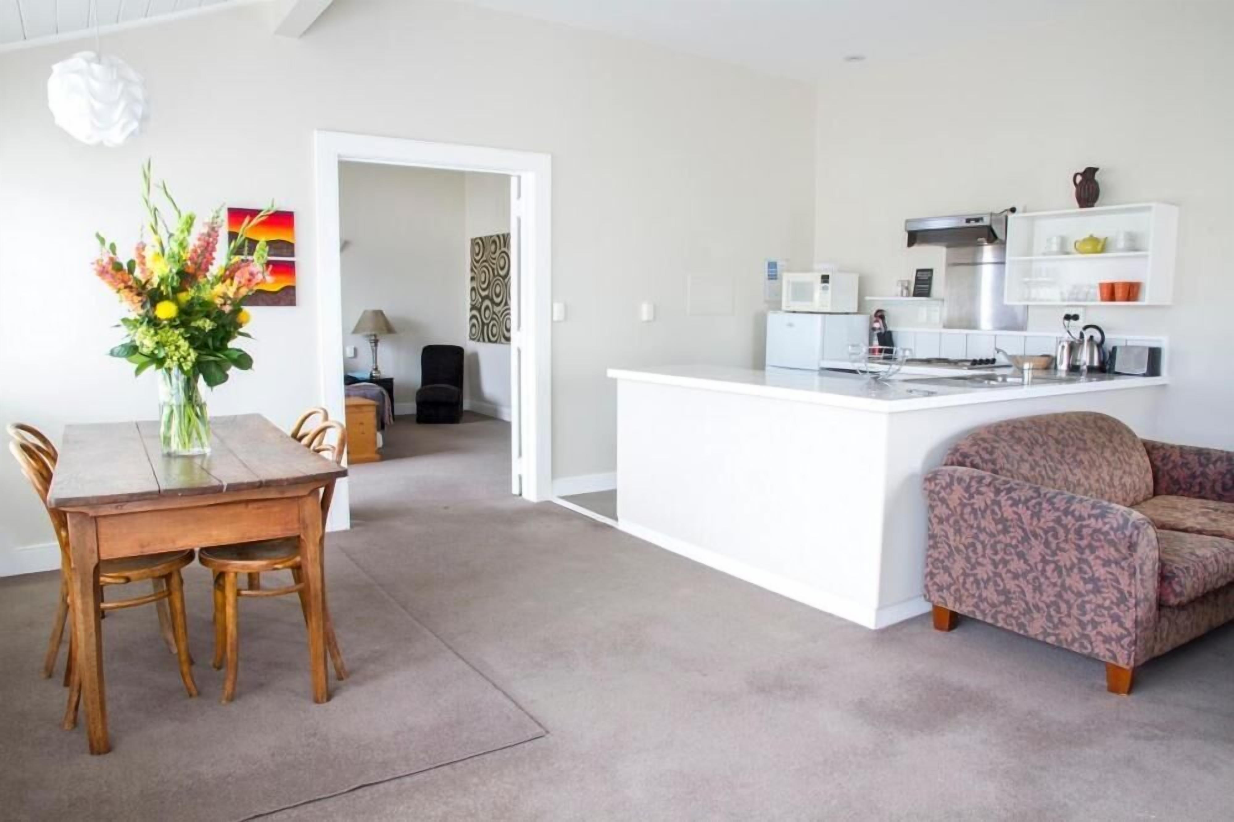 A modern kitchen with white cabinetry, a built-in island, and a dining area with a wooden table and chairs.