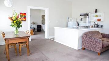 A modern kitchen with white cabinetry, a built-in island, and a dining area with a wooden table and chairs.
