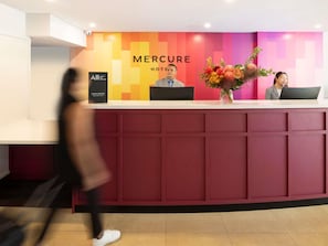 A hotel reception desk with a modern design, featuring a prominent 'Mercure Hotel' sign and a floral arrangement. - Mercure Perth On Hay (Perth)