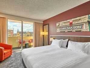 Habitación de hotel con una cama grande, una silla roja y vistas a una iglesia, además de un cartel que dice 'FIRE STATION'.