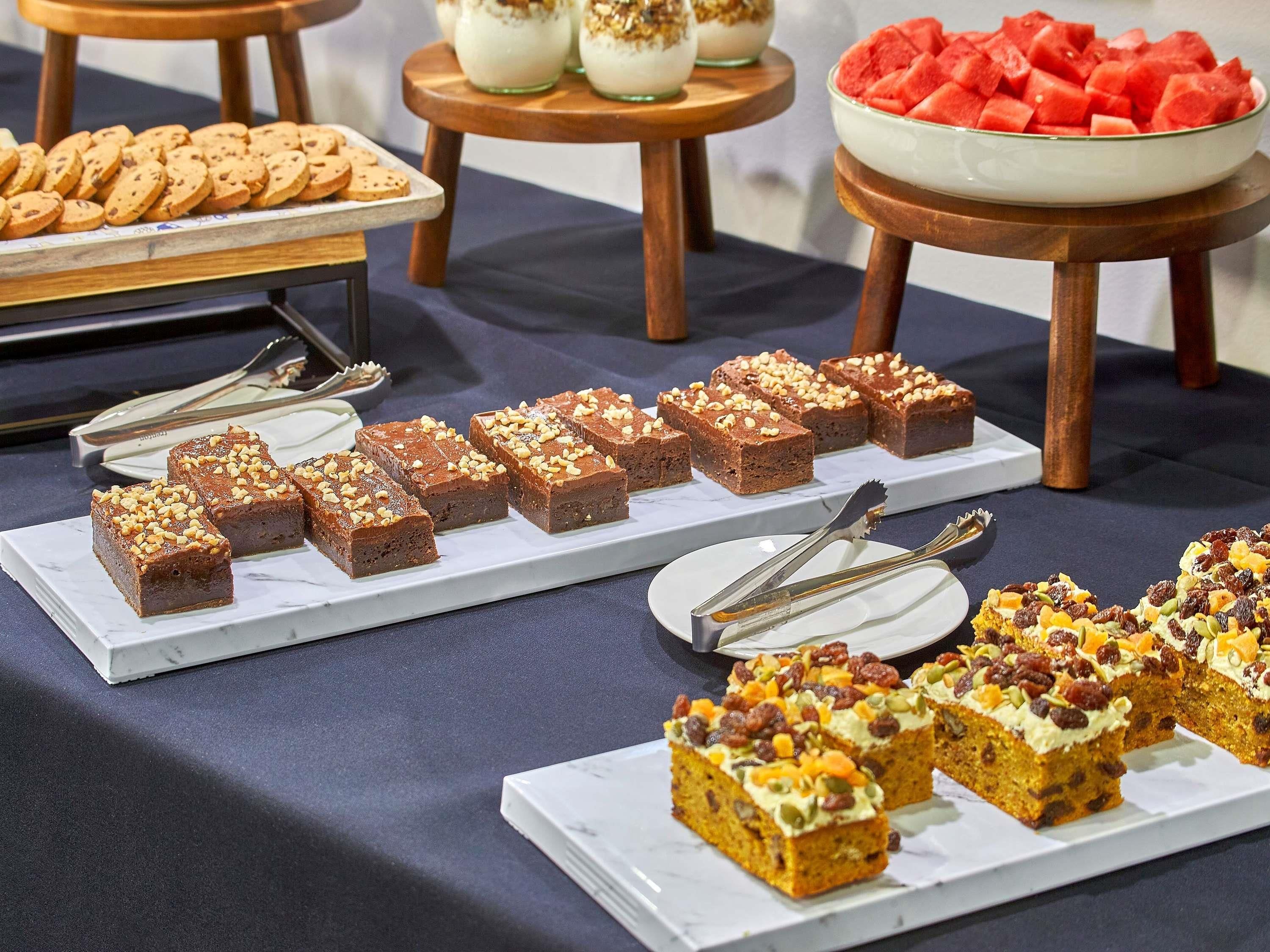 A buffet table with various desserts, including brownies and fruit.