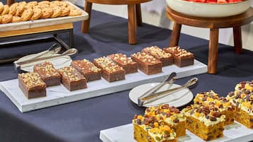 Taula de buffet amb diferents postres, incloent pastissos de xocolata i fruita.
