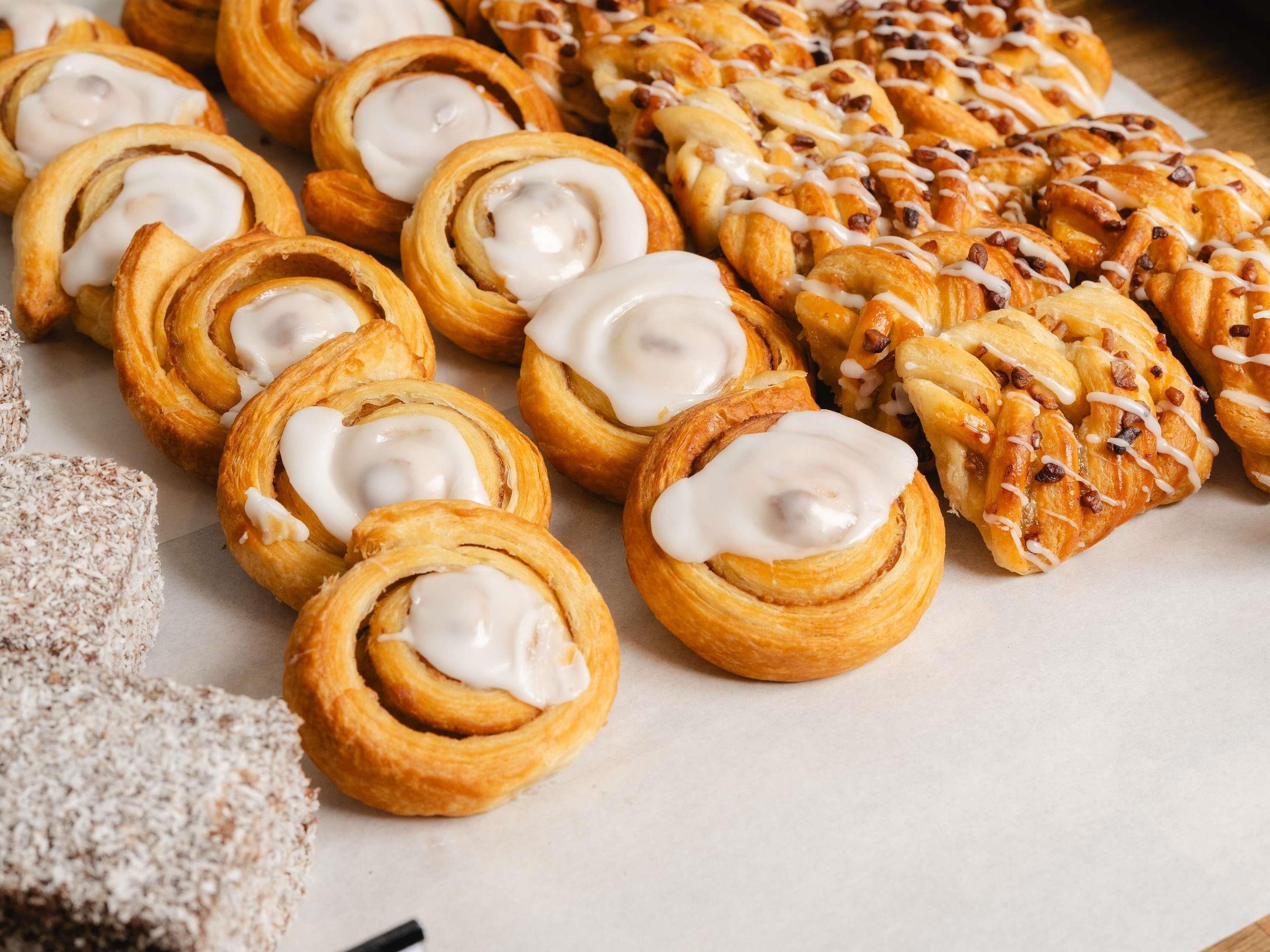 A variety of pastries including cinnamon rolls and a large pastry with nuts and icing.