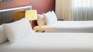A hotel room with two beds, a nightstand with a lamp, and a view of the outside through sheer curtains. - Mercure Perth On Hay (Perth)