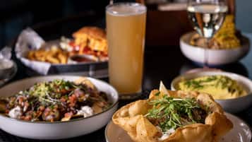 A dining table with various dishes, a glass of beer, and a glass of white wine.