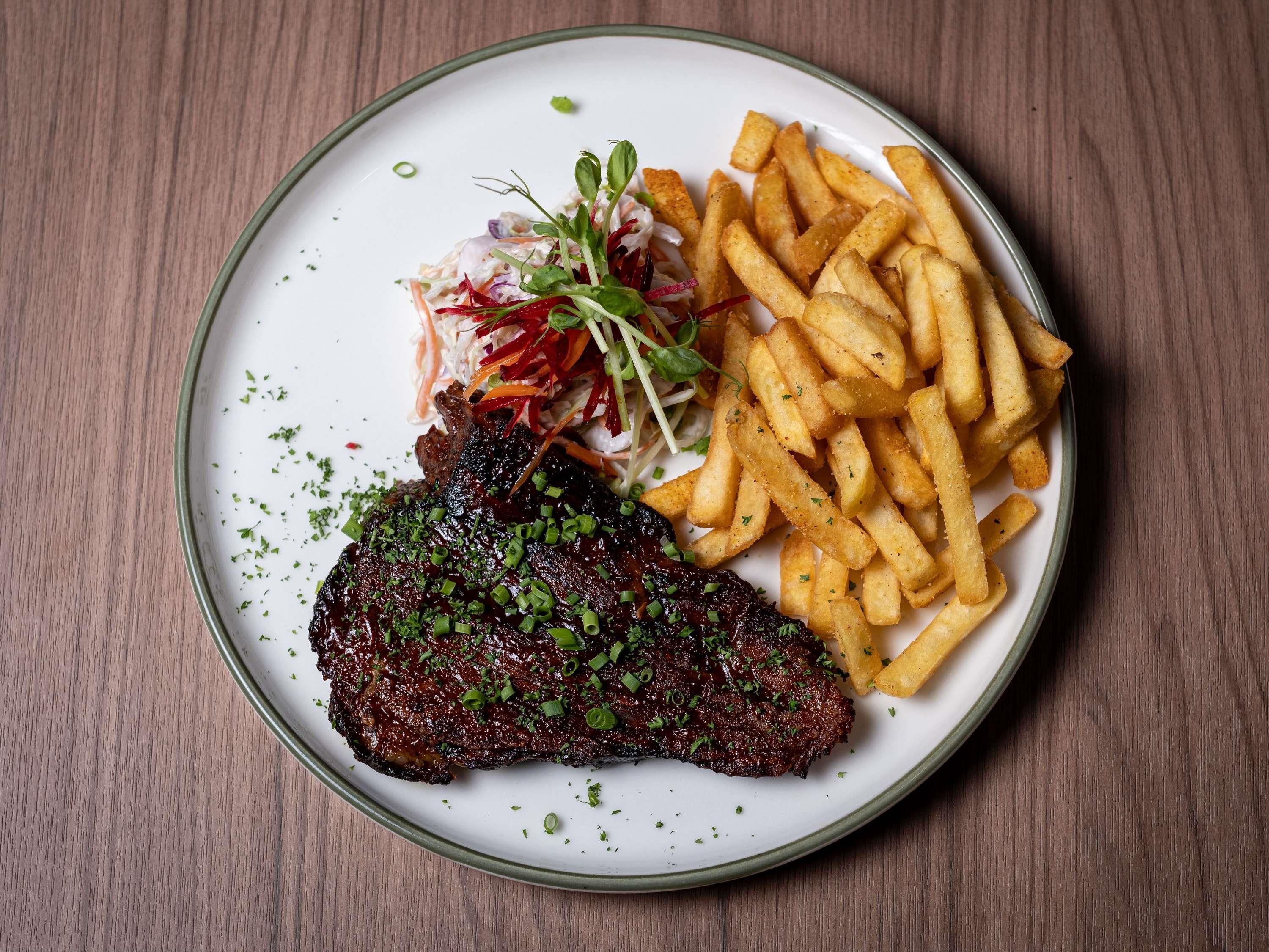 A plate with a steak, fries, and a salad.