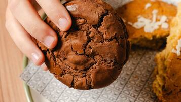 Una mano sosteniendo una galleta de chocolate con textura rugosa.