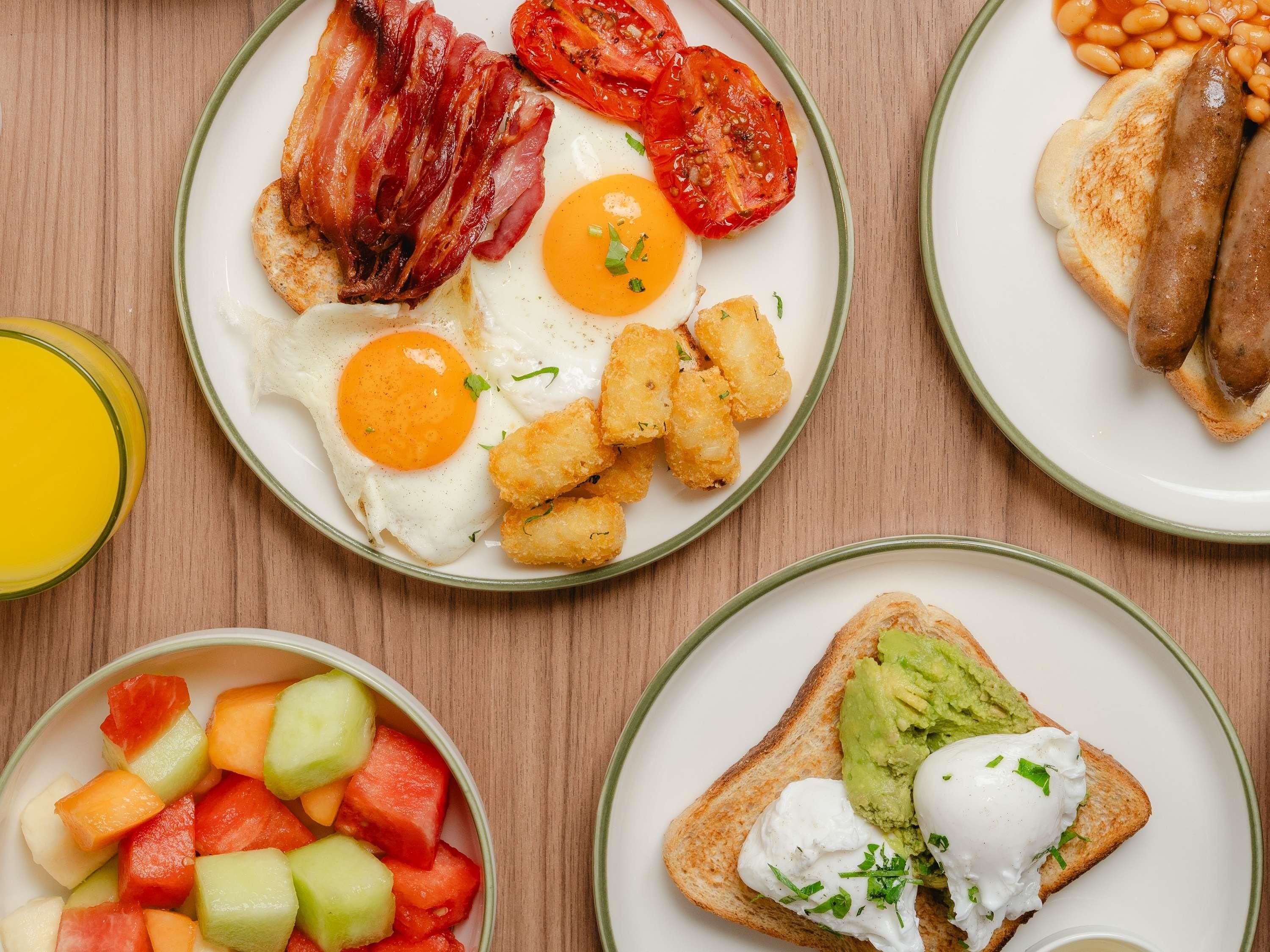 Ein Frühstücksteller mit Eiern, Speck, Tomaten, Bohnen und Toast.