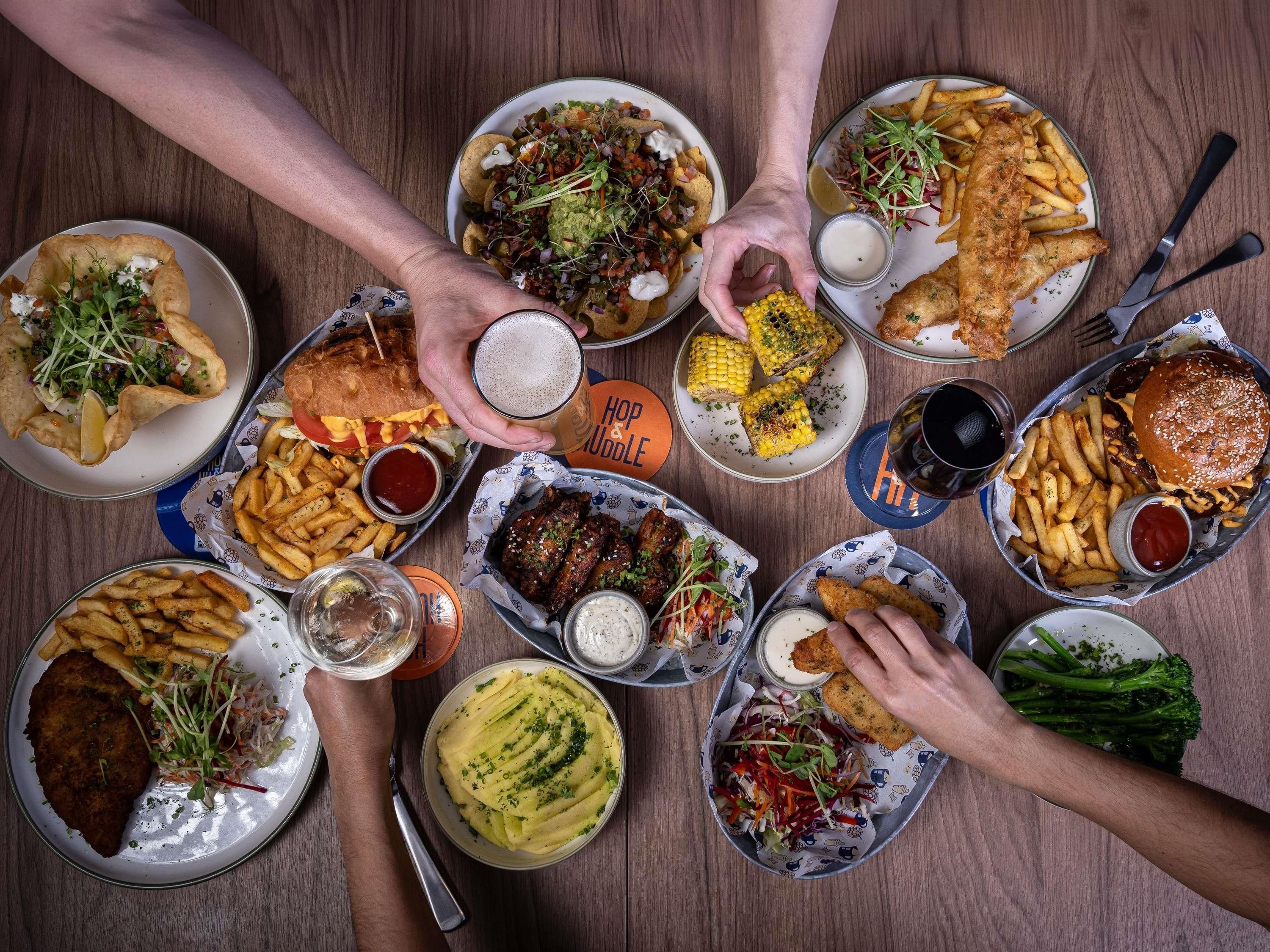 A variety of dishes on a table, including a burger, fries, and a fish dish.