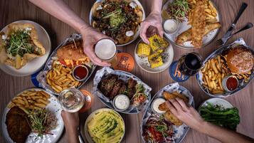 A variety of dishes on a table, including a burger, fries, and a fish dish.
