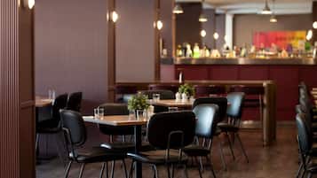 A restaurant with tables and chairs, a bar area, and a decorative plant on the tables.