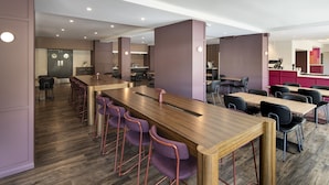 A modern conference room with long tables and purple chairs, a kitchen area, and a bar. - Mercure Perth On Hay (Perth)