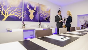 A conference room with a reception desk, a large painting of a deer, and a modern interior design. - Hotel Merkur (Baden-Baden)