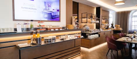A modern hotel lobby with a reception desk, buffet area, and seating area.