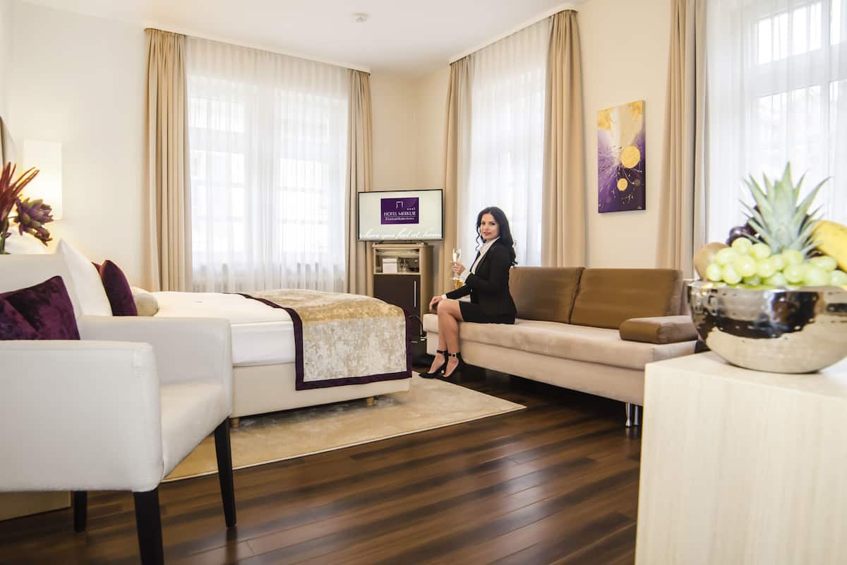 Una habitación de hotel moderna con cama, sofá, televisor y frutero.