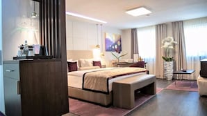 A modern hotel room with a large bed, bedside tables, a desk, and a chair. - Hotel Merkur (Baden-Baden)