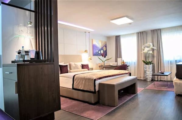 A modern hotel room with a large bed, bedside tables, a desk, and a chair. - Hotel Merkur (Baden-Baden)