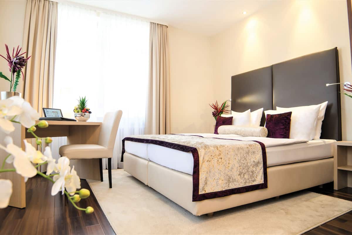 Una habitación de hotel moderna con una cama grande, un escritorio y una silla.
