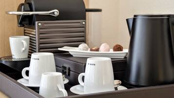 A tray with coffee-making equipment, white cups, and a plate with pastries.