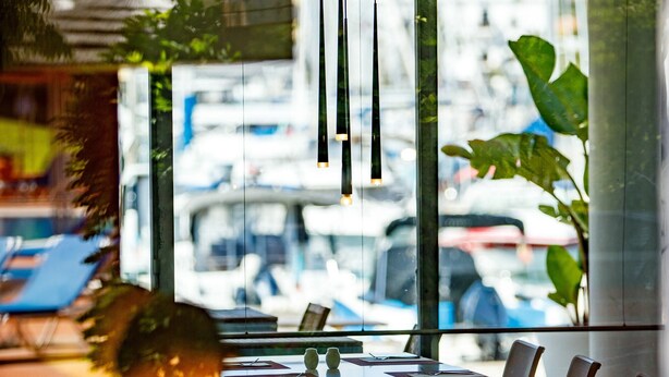 Un restaurant doté d’une terrasse, de grandes fenêtres et de luminaires suspendus.