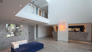 A modern lobby with a marble floor, a reception desk, and a blue seating area. - Marina Club I (Lagos)