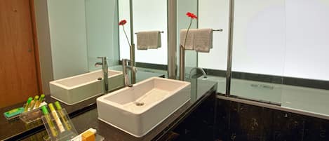 A modern bathroom with two sinks, a large mirror, and a bathtub.