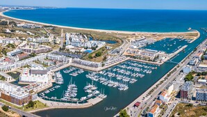 An aerial view of a marina with numerous boats docked, surrounded by residential buildings and a beach. - Marina Club Suite Hotel (Lagos)