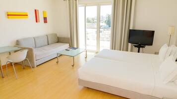 Una camera d'albergo moderna con un divano, un letto, una televisione e un tavolo.