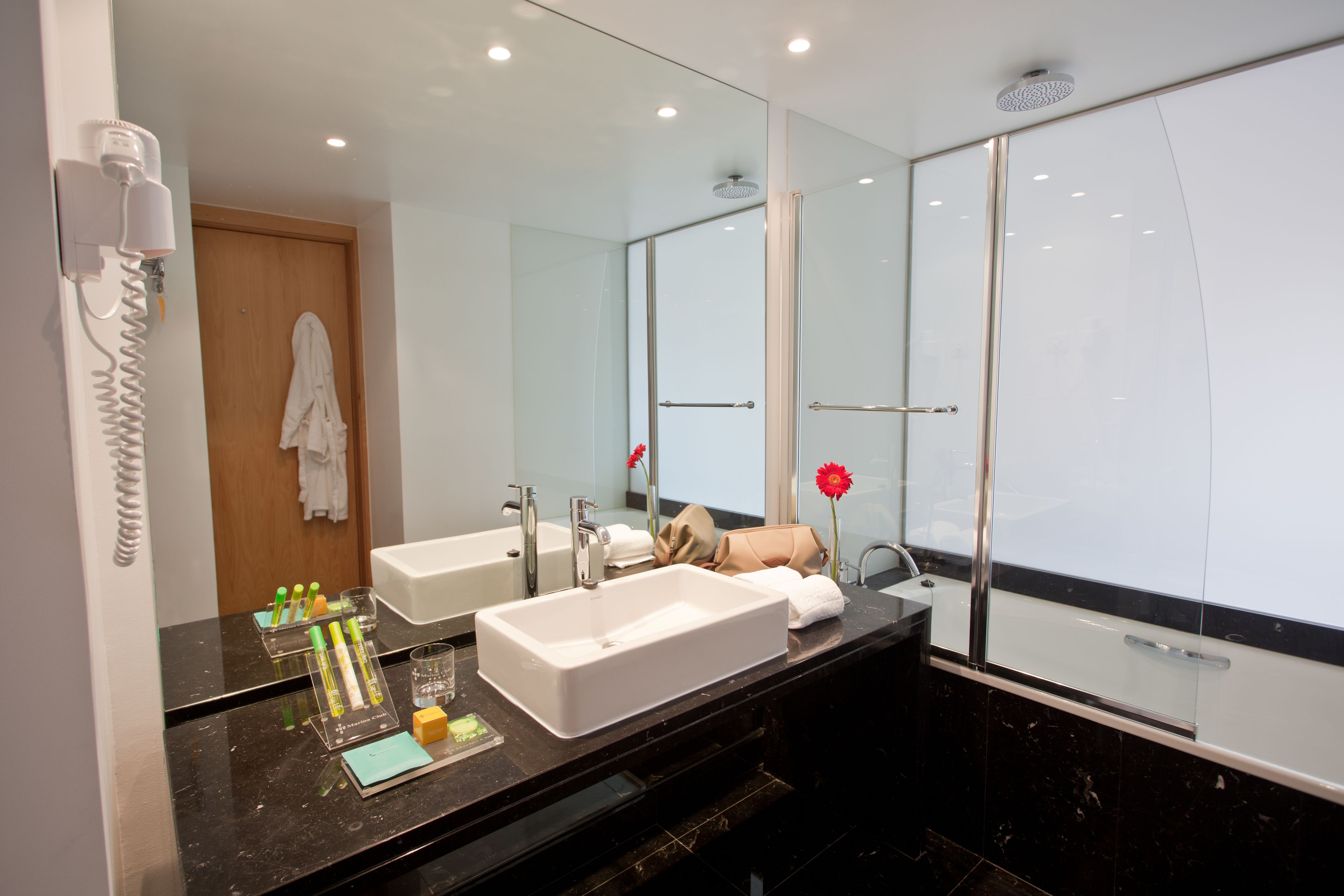Un baño moderno con dos lavabos, un espejo grande y una cabina de ducha de vidrio.