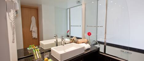 A modern bathroom with two sinks, a large mirror, and a glass shower enclosure.