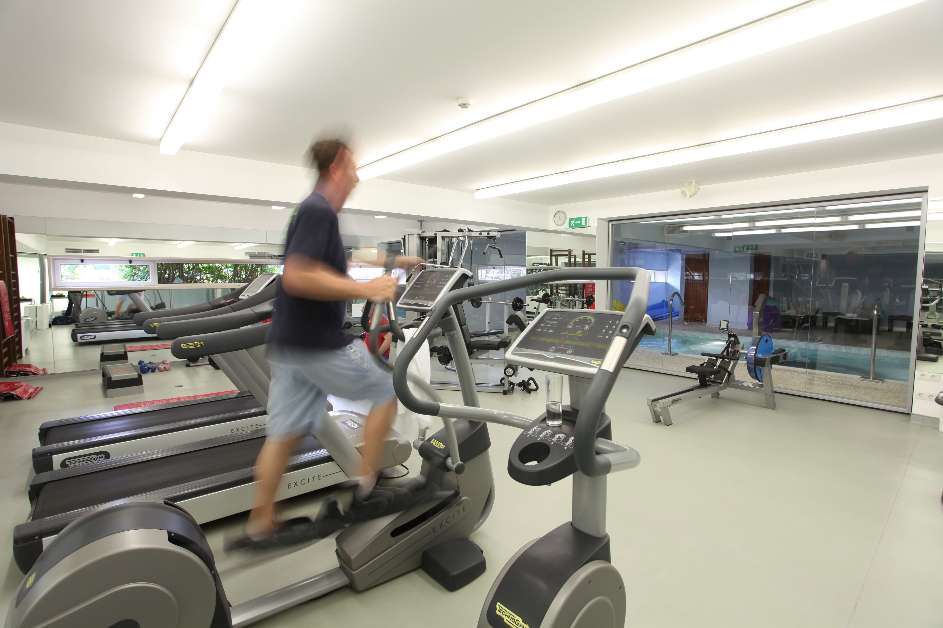 A modern gym with treadmills, exercise equipment, and a glass wall.