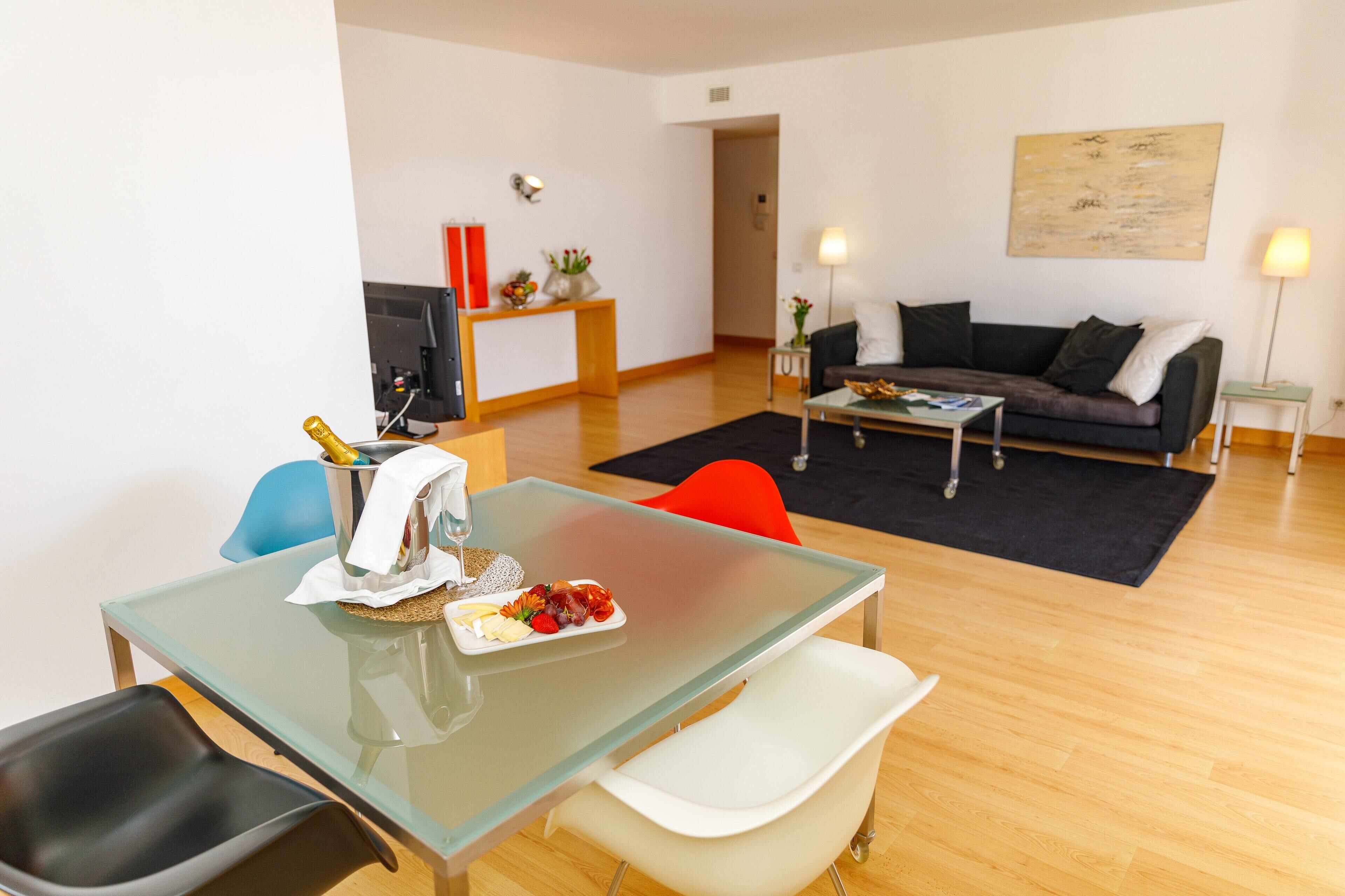 A modern living room with a glass dining table, a sofa, and a coffee table.
