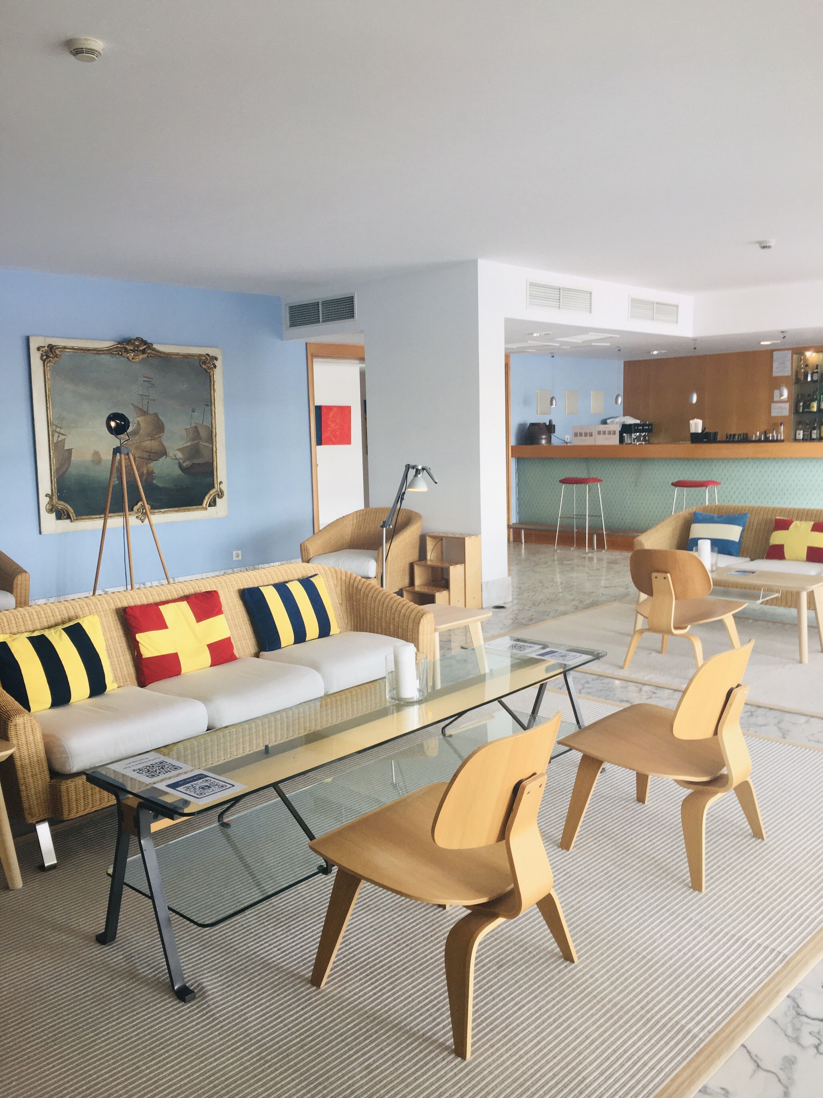 A modern living room with a sofa, chairs, a coffee table, and a painting on the wall.