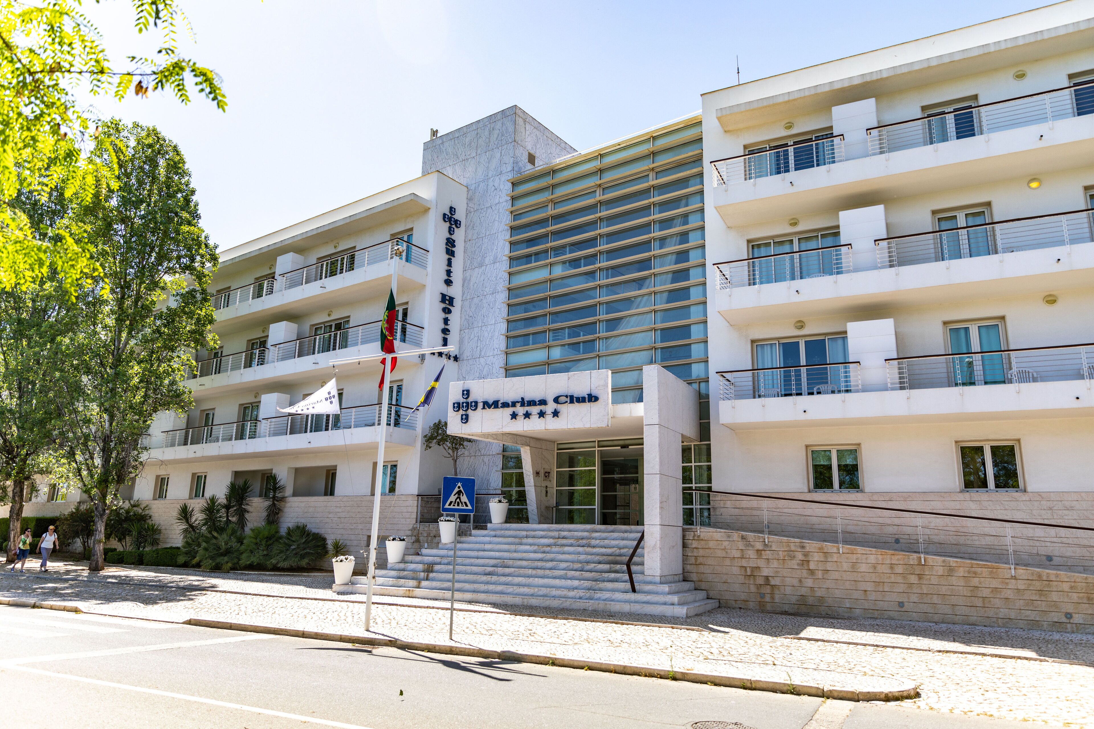 Un hôtel doté d’une façade moderne, de nombreux balcons et d’une entrée imposante avec des marches.