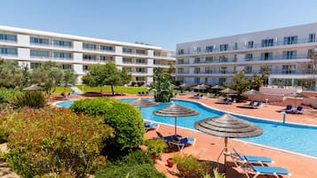 A hotel with a swimming pool, sun loungers, and a well-maintained garden.